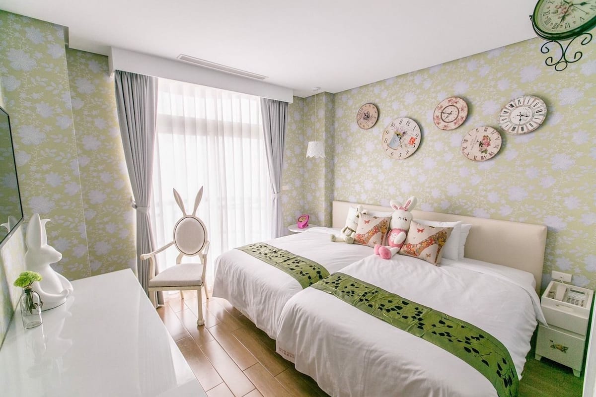 A bedroom with a large bed, a chair, a dresser, and a wall clock.