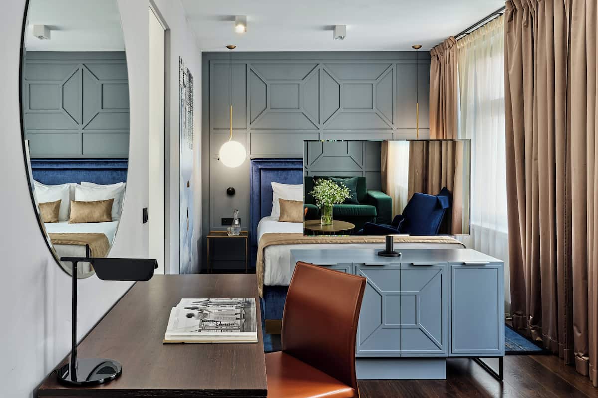 Een moderne hotelkamer met een groot bed, een bureau, een stoel, een bank, een salontafel en een spiegel.