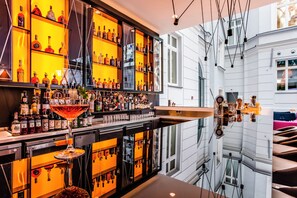A bar area with shelves of liquor bottles, a bar counter, and a large mirror reflecting the interior. - Hotel Indigo Warsaw - Nowy Swiat by IHG (Warsaw)
