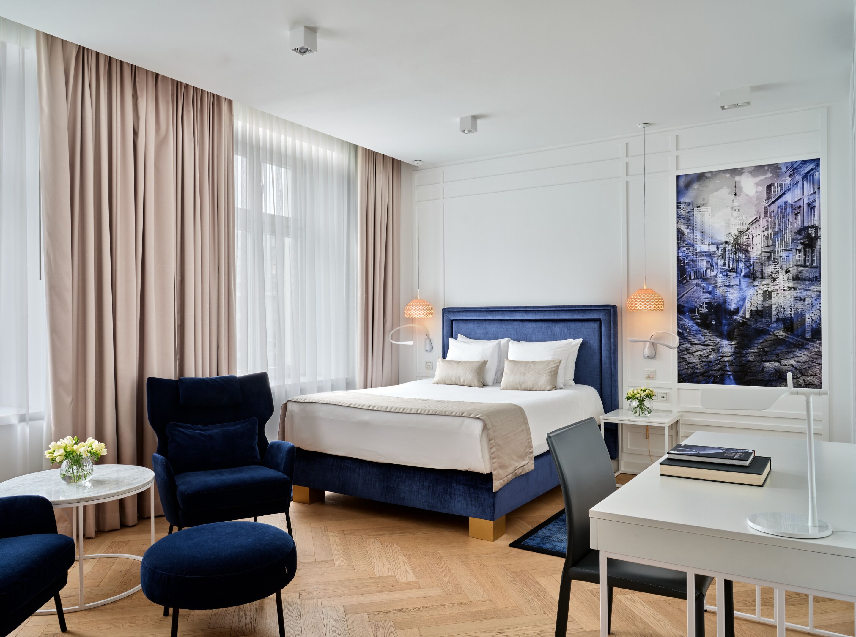 Una habitación de hotel con una cama grande, dos mesitas de noche, un escritorio y una silla.