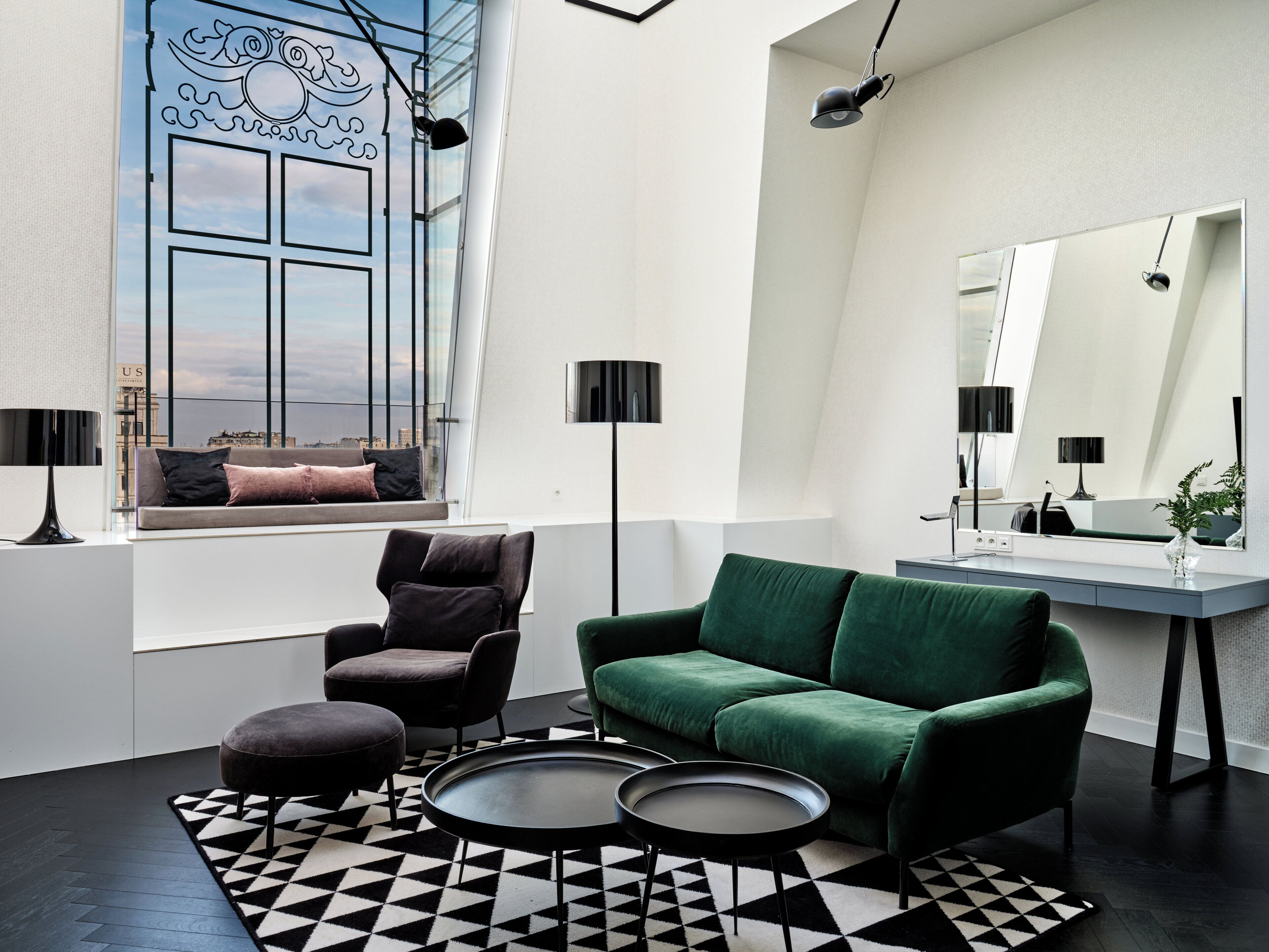 A modern living room with a green sofa, a black armchair, and a round coffee table.