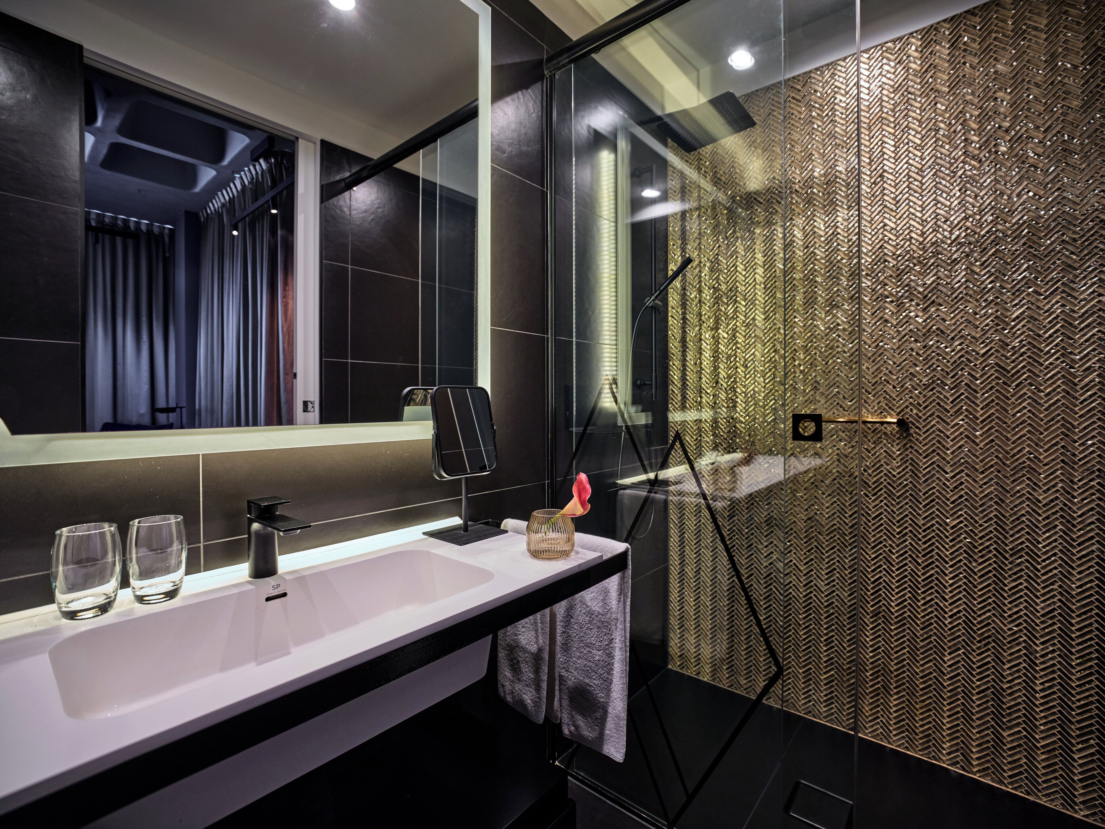 A modern bathroom with a large mirror, a sink, and a shower area.