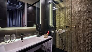 A modern bathroom with a large mirror, a sink, and a shower area.