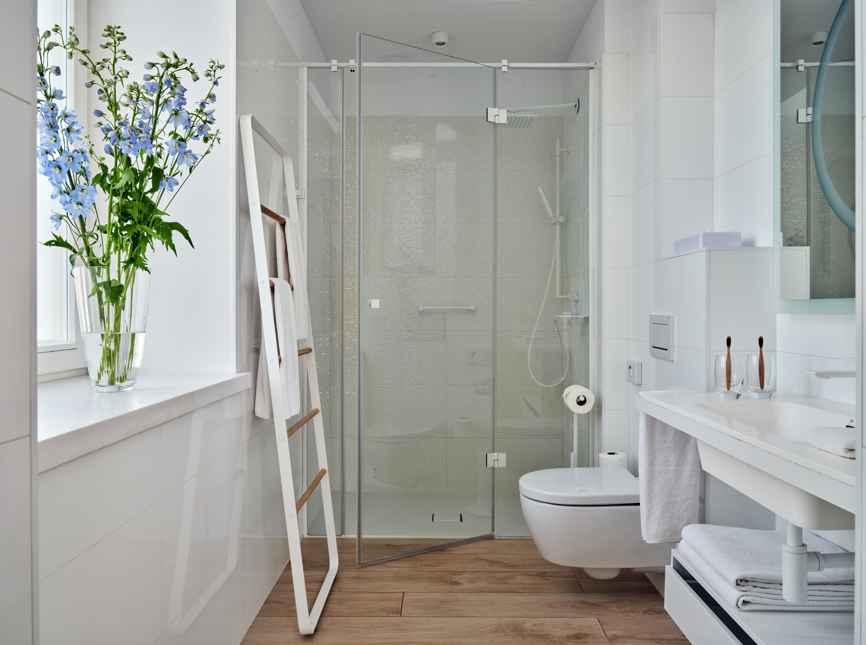 Un baño moderno con cabina de ducha de vidrio, inodoro blanco y tocador con espejo.