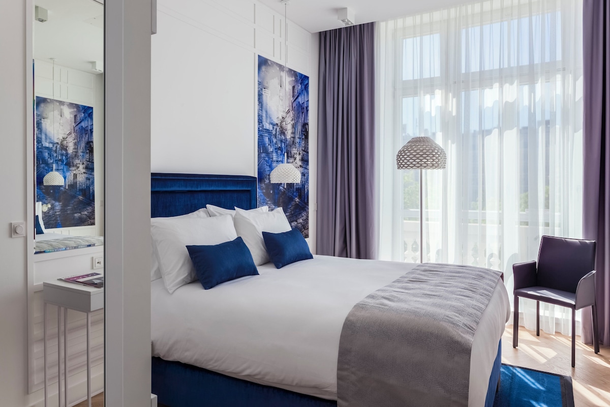 Ein modernes Hotelzimmer mit einem großen Bett, einem Schreibtisch und einem Stuhl.