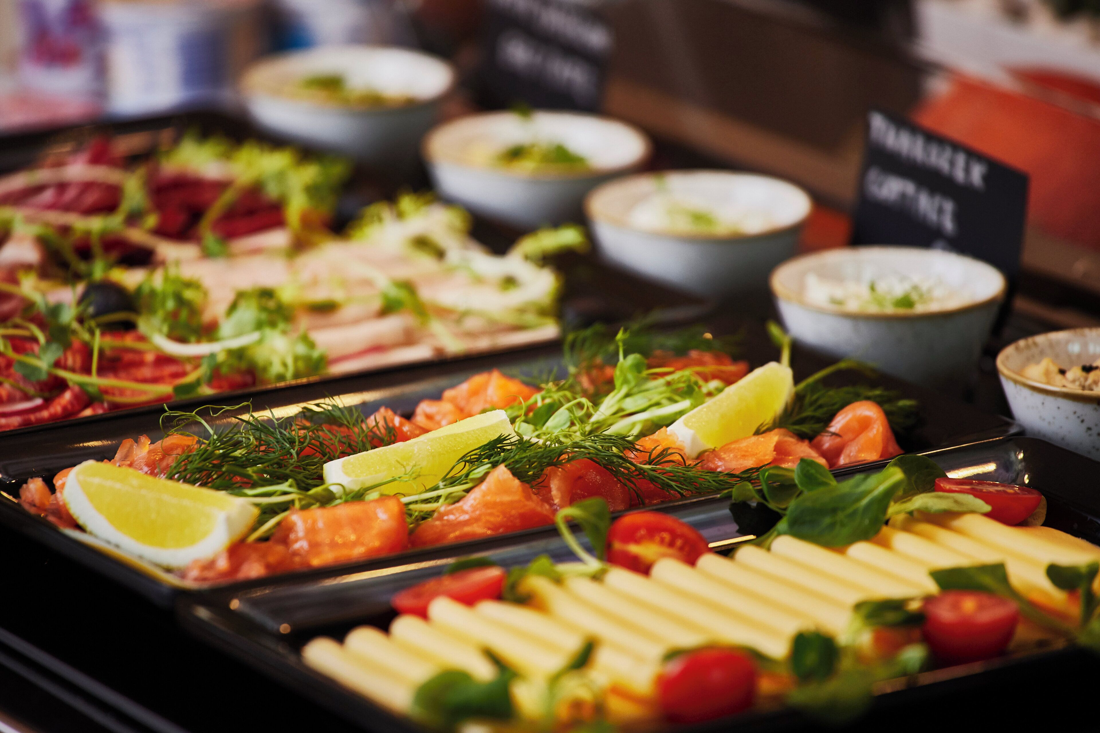 A buffet with various food items including salmon, vegetables, and a selection of sauces.