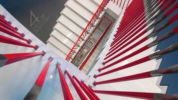 A modern architectural structure with a series of red and white elements, possibly a staircase or ramp, and a grey sky in the background.