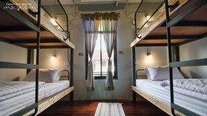 Un dormitorio con dos literas, suelo de madera, alfombra a rayas y una ventana con cortinas.
