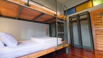 A bunk bed room with a wooden floor, metal ladder, and a mesh door.