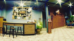 Una zona de bar con mostrador, taburetes y una estantería decorativa con objetos.