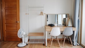 A room with a wooden door, a white fan, a desk with two chairs, and a mirror. - Hongdae One House (Seoul)