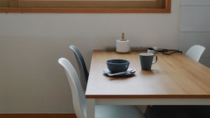 A wooden table with a blue bowl and mug, a white tissue roll, and a power cord. - Hongdae One House (Seoul)