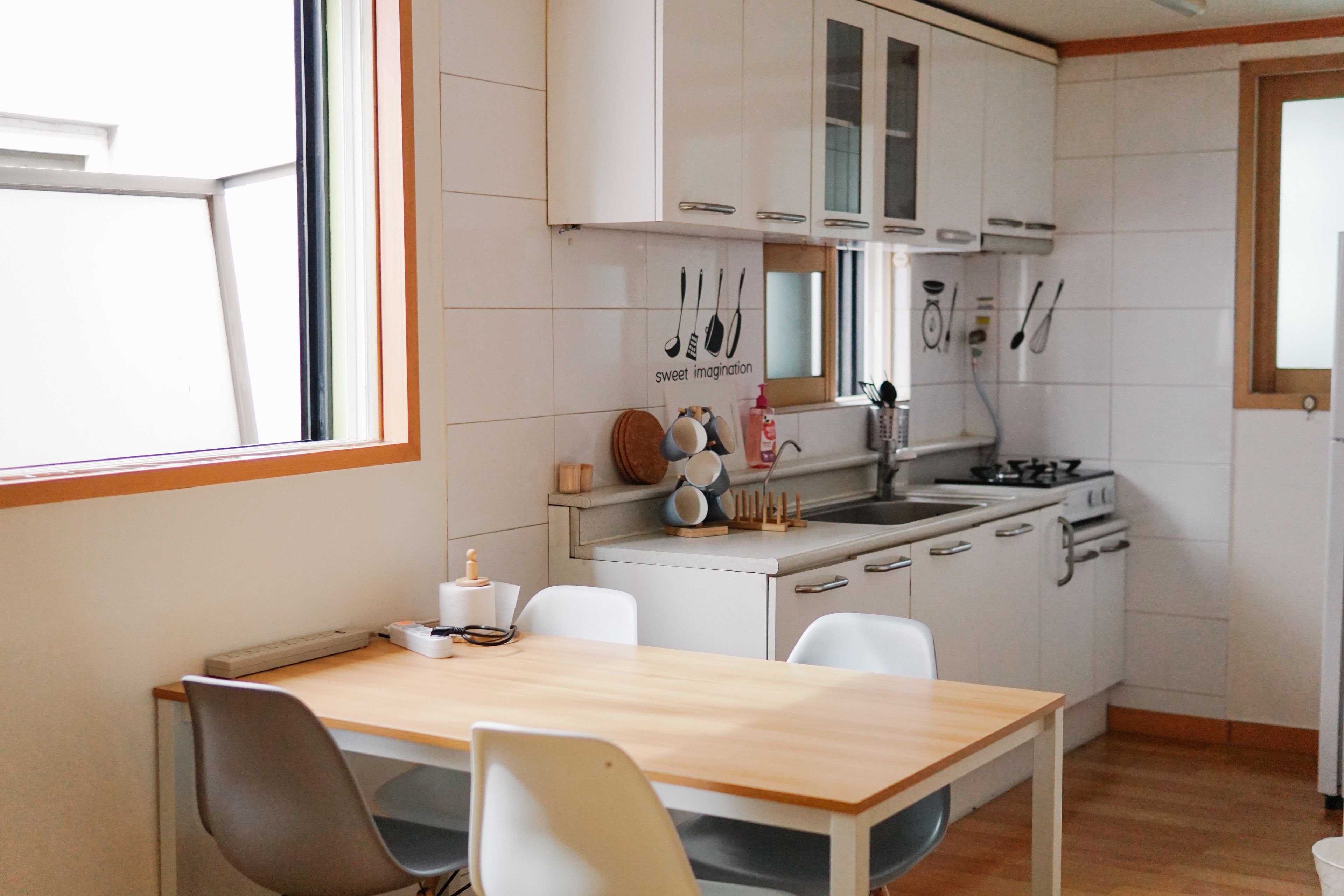 Una cocina compacta con armarios blancos, una mesa de madera y una ventana.