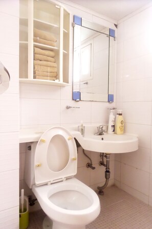 Een badkamer met toilet, wastafel en spiegel.