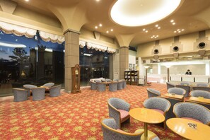 A hotel lobby with a red carpet, seating areas, and a reception desk. - Mikuni Ocean Resort & Hotel (Sakai)