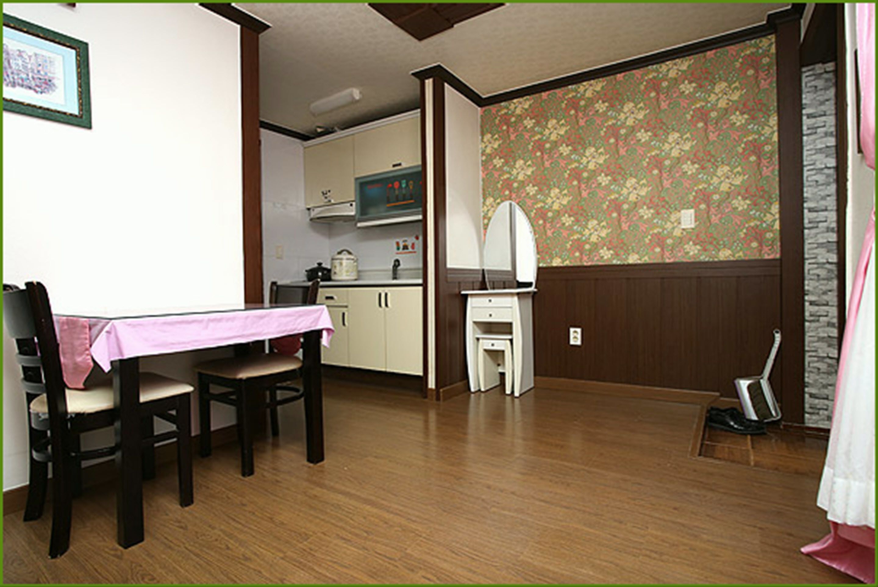 Un comedor con mesa y sillas, una kitchenette al fondo, y una pared con diseño.