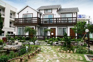 A two-story building with a balcony, stone pathway, and garden area.