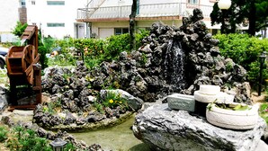 A garden with a water feature, rocks, and a wooden structure.