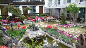 A courtyard with a pond, benches, and a wooden table.