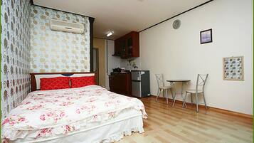 Ein Schlafzimmer mit Bett, einer kleinen Küchenzeile und einem Essbereich.