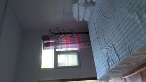 Ein Zimmer mit einem Bett, einem Vorhangfenster und einer Decke mit herunterhängenden Gegenständen.