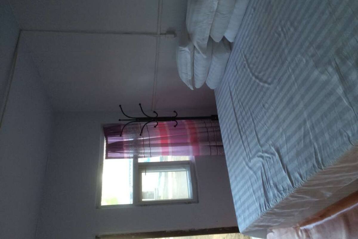 Quarto com uma cama, janela com cortinas e objetos pendurados no teto.