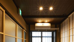 A hallway with sliding doors, wooden flooring, and recessed lighting.