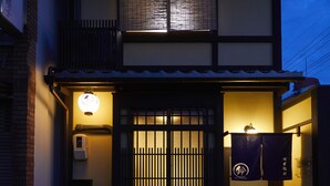 A traditional Japanese house with a tiled roof, a wooden gate, and a small porch area.