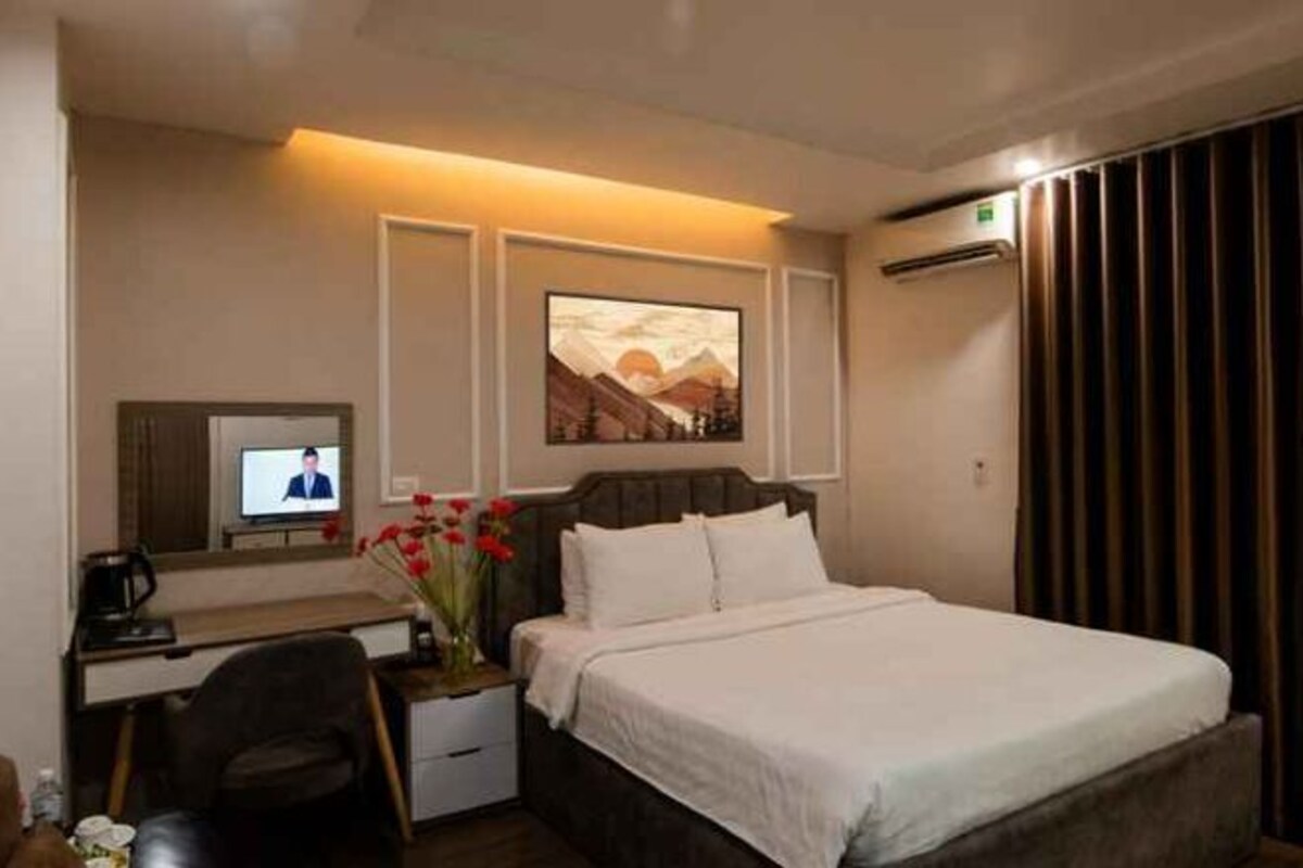 Habitación de hotel con cama, escritorio con computadora, televisión y aire acondicionado instalado en la pared.