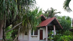 A small house with a red roof, surrounded by lush greenery and palm trees. - Chill Beach Resort (Pathio)