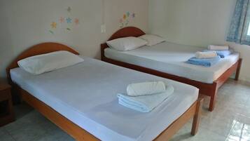 Two single beds with wooden frames and white linens, a small wooden nightstand, and a wall with colorful flower decals.