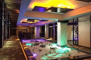 A modern hotel lobby with a pool area, a reception desk, and a decorative column. - Delight Empire Hotel (Dongguan)