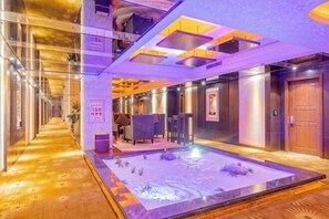 Un vestíbulo de hotel con una zona de estar central, un mostrador de recepción y una recepción.