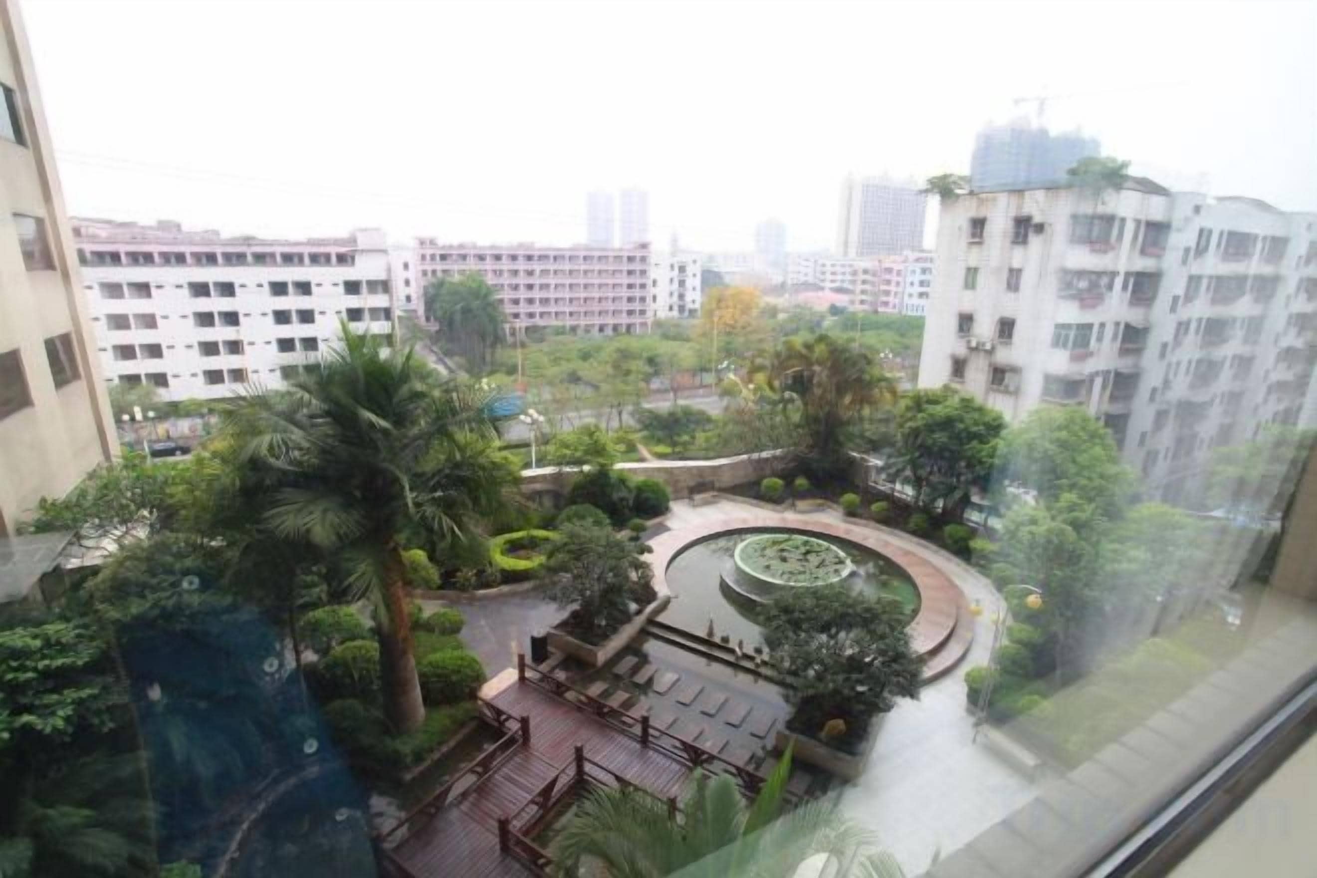 A residential building with a rooftop garden, a circular water feature, and a view of the cityscape.