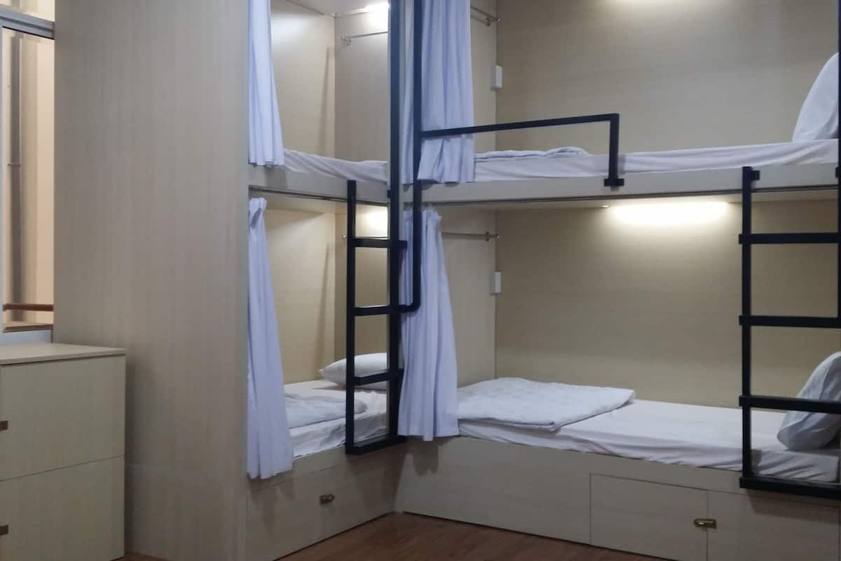 A bunk bed room with a wooden cabinet and a small window.