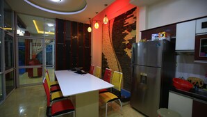A modern kitchen with a dining area, featuring a white table, colorful chairs, and a built-in refrigerator. - My Homestay - Hostel (Nha Trang)