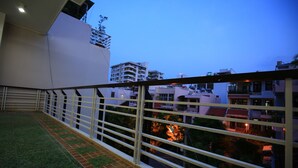 A balcony with a metal railing, a green carpet, and a view of buildings in the background. - My Homestay - Hostel (Nha Trang)