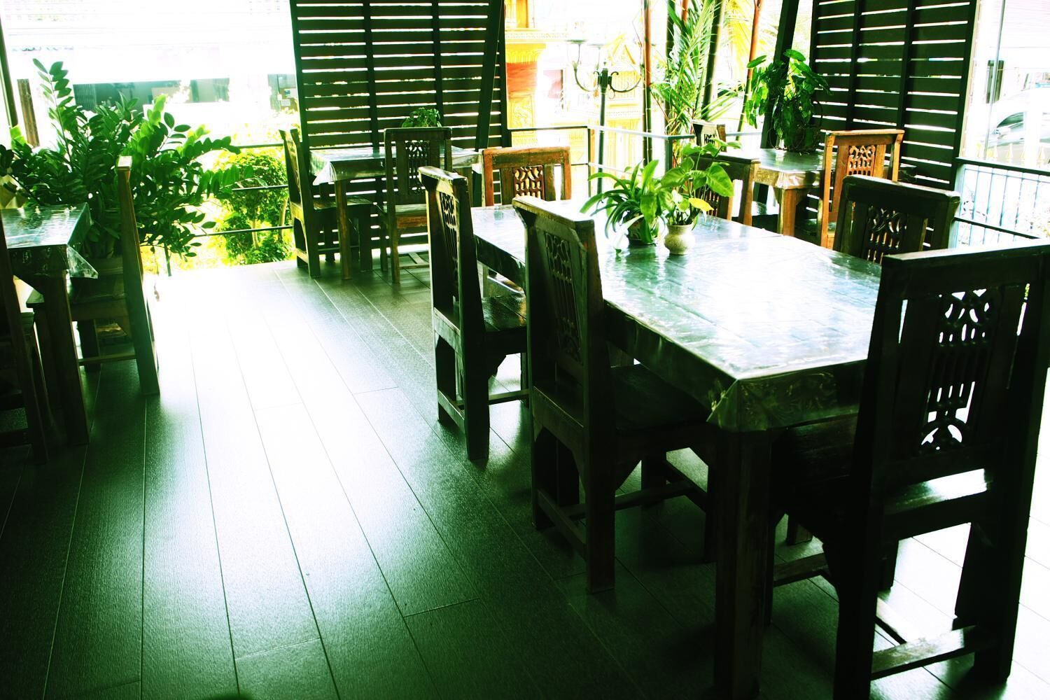 A dining area with wooden furniture and potted plants.