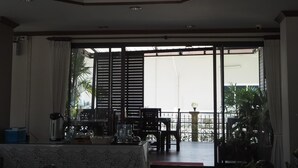 A spacious living area with a large sliding glass door leading to a balcony. - Ritzy House Hotel (Chumphon)