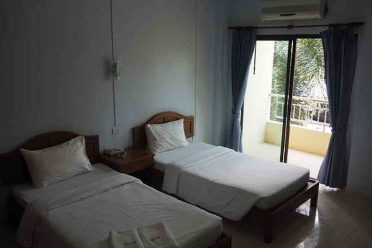 A hotel room with two beds, a balcony, and a view of the outdoors.