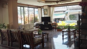 A spacious living area with a sofa set, a TV, and a coffee table. - Ritzy House Hotel (Chumphon)