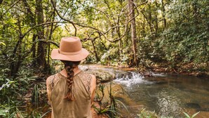 A person standing by a stream in a forested area. - Ahaspokuna by Eco Team (Balangoda)