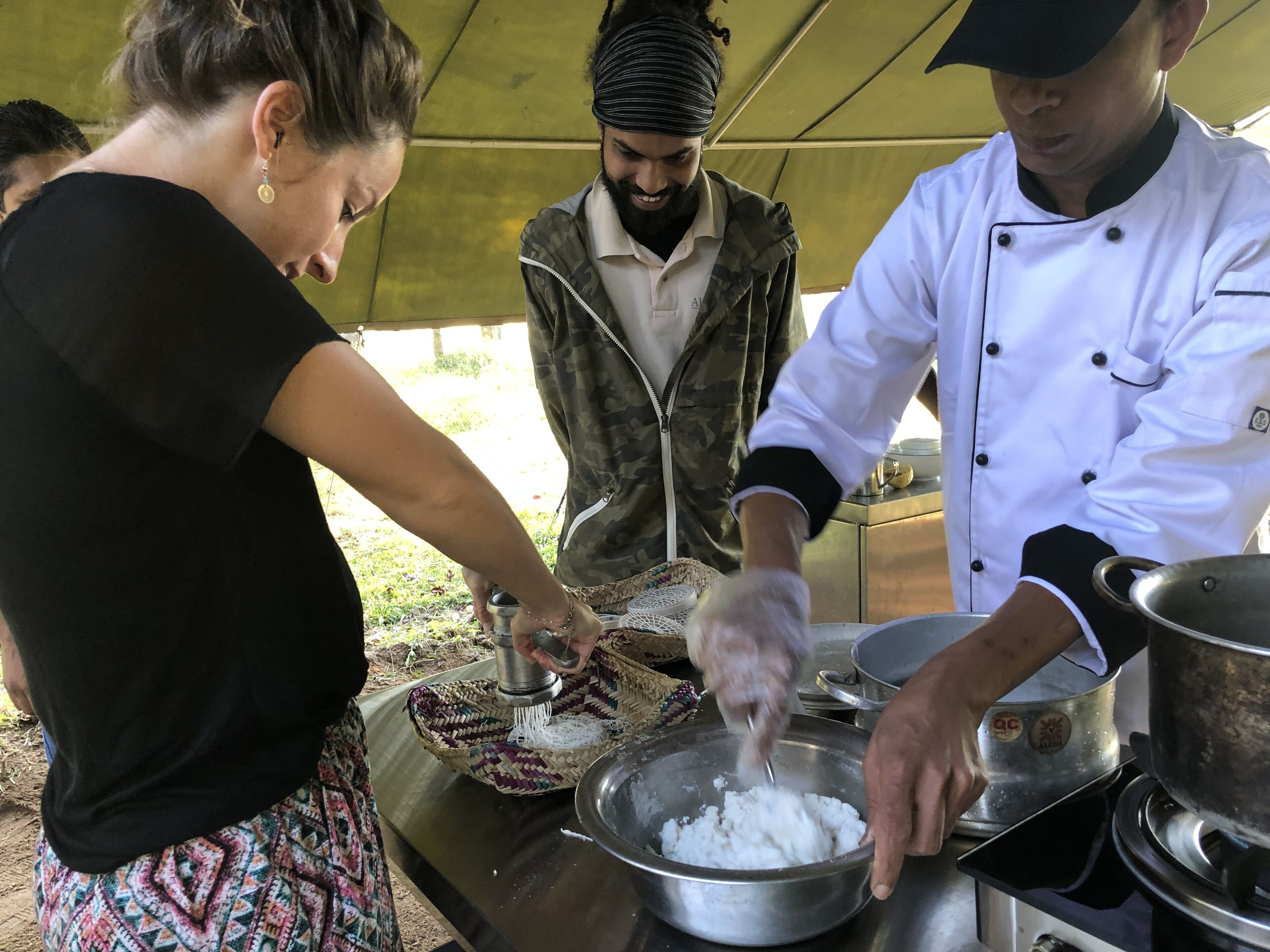 A group of people preparing food outdoors under a tent.