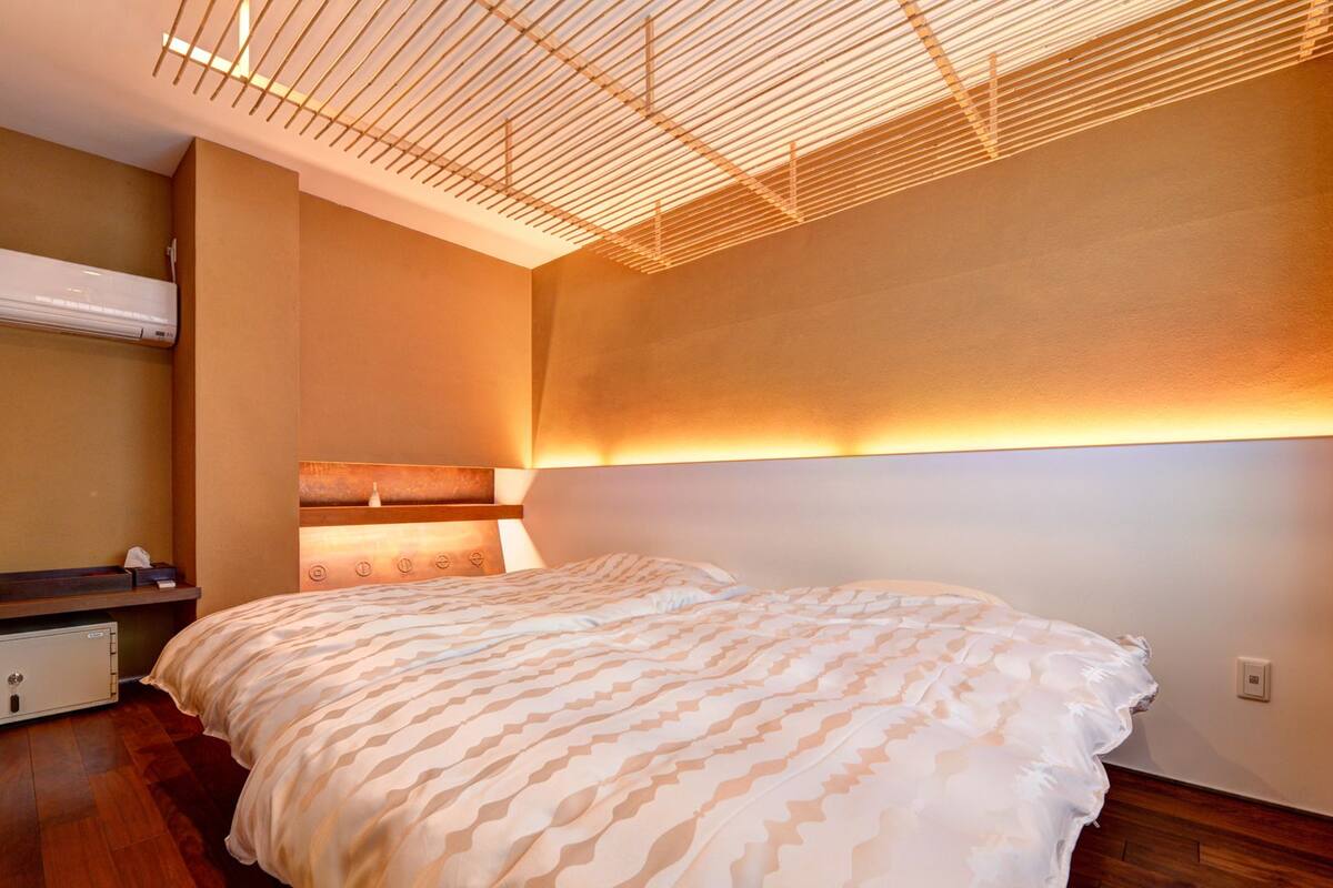 Ein modernes Schlafzimmer mit einem großen Bett, Holzboden und einer Decke mit einem Gittermuster.