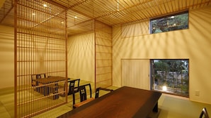 A traditional Japanese room with tatami flooring, a low table, and a sliding door leading to a garden. - Shouen (Izumo)