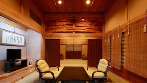 A conference room with a wooden ceiling, two chairs, a table, a TV, and a sliding door. - Shouen (Izumo)