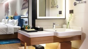 Ein modernes Hotelbad mit einem großen Spiegel, zwei Waschbecken und einem Waschtisch mit Stauraum.