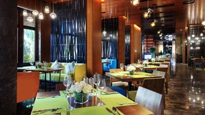 Ein Restaurant mit mehreren Esstischen, Stühlen und hängenden Pendelleuchten.