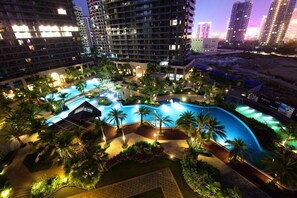 A resort with a large swimming pool surrounded by palm trees and well-lit walkways. - Hampton by Hilton Sanya Bay (Sanya)