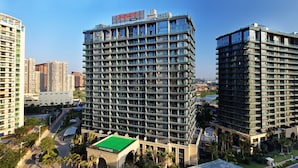Ein Hochhaus-Hotel mit mehreren Etagen, großen Fenstern und einem gebäudeartigen Bauwerk mit Gründach im Vordergrund.